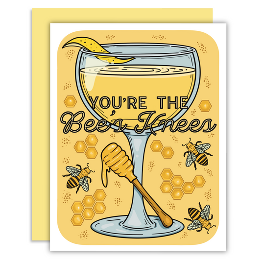 A cocktail with honey dipper with text that says you’re the bees knees with honeycombs and bees on a card