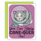 A gray cat with green eyes in a loaf position in a cone on a purple background on a greeting card
